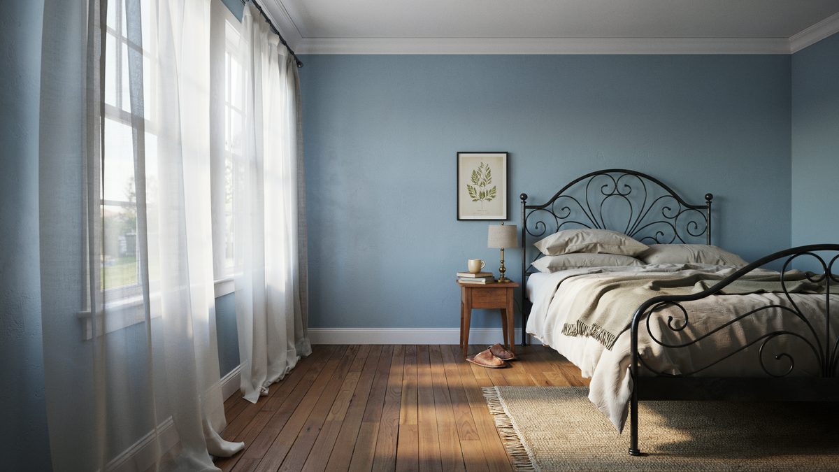 Light blue room with a black wrought iron bed and warm hardwood planks