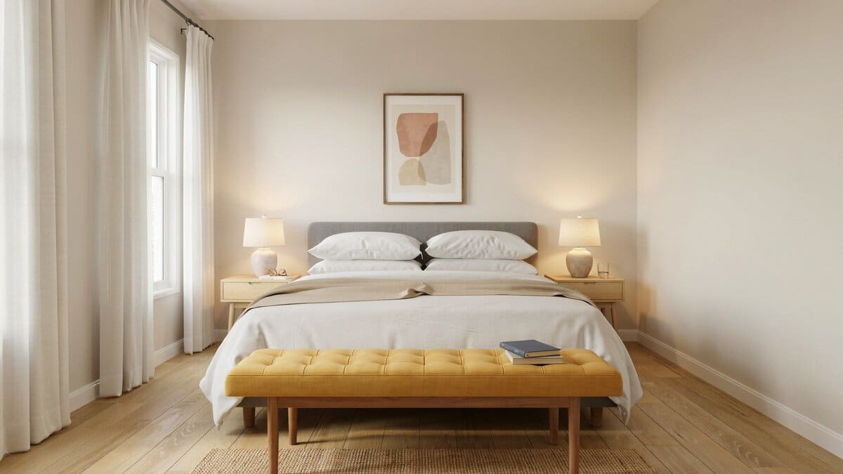 Yellow tufted bench stretches across the foot of a neutral gray bed