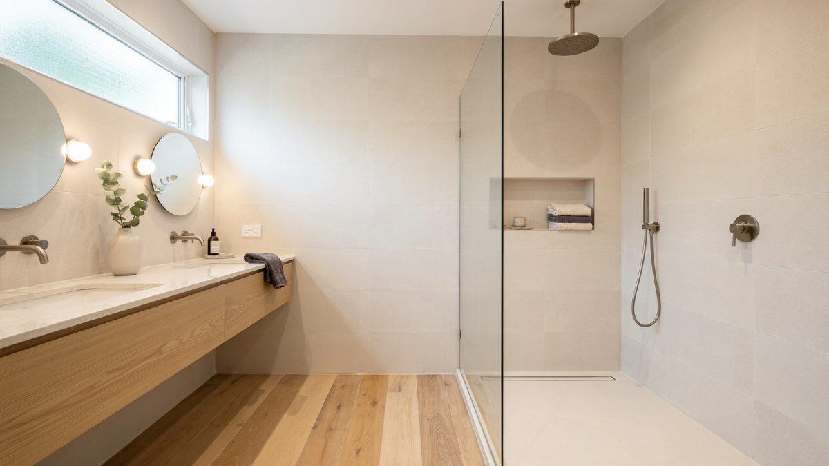 Floating wood vanity with super white quartz counter beside a doorless walk in shower