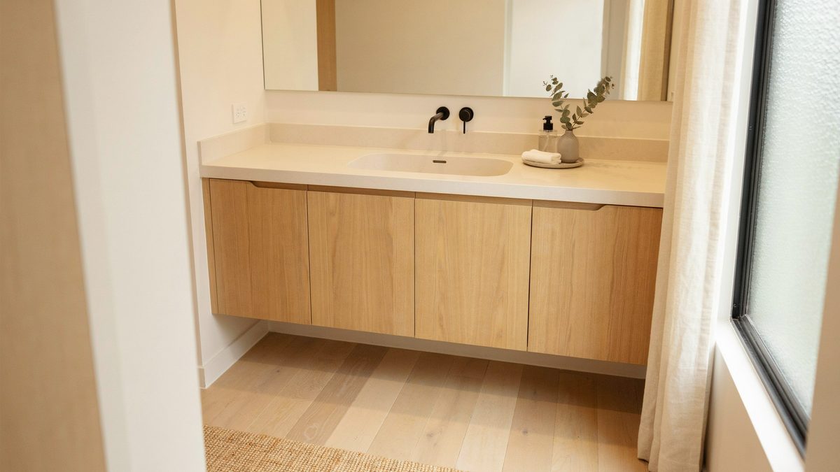 Light oak vanity with a seamless cream solid surface counter and integrated sink