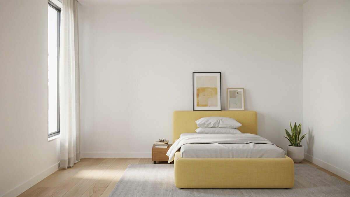 Low yellow platform bed rests on a soft gray rug against white walls