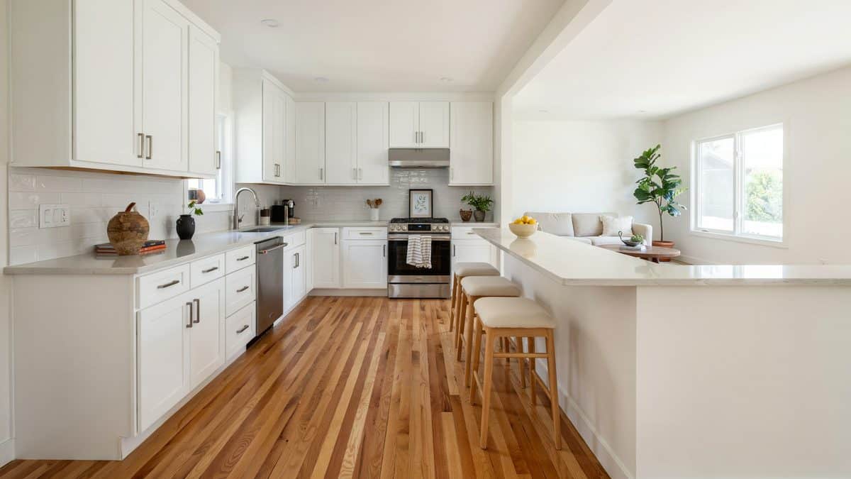 White cabinets end in a peninsula counter with three wooden stools tucked under