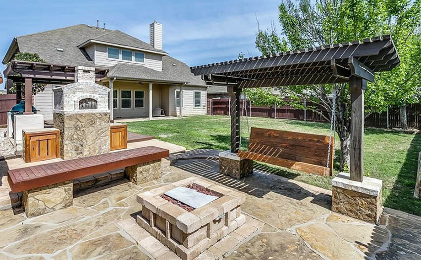 Pergola swing fire pit on backyard flagstone patio