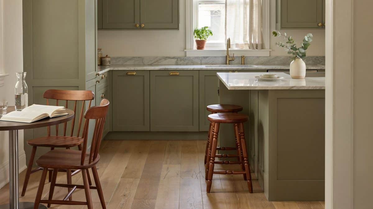 Compact olive kitchen with a marble topped island and warm sienna wood stools