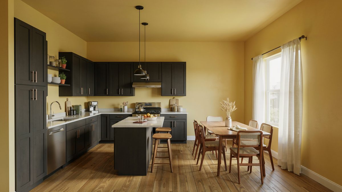 Near black cabinets against mustard walls with a hickory floor and six chairs
