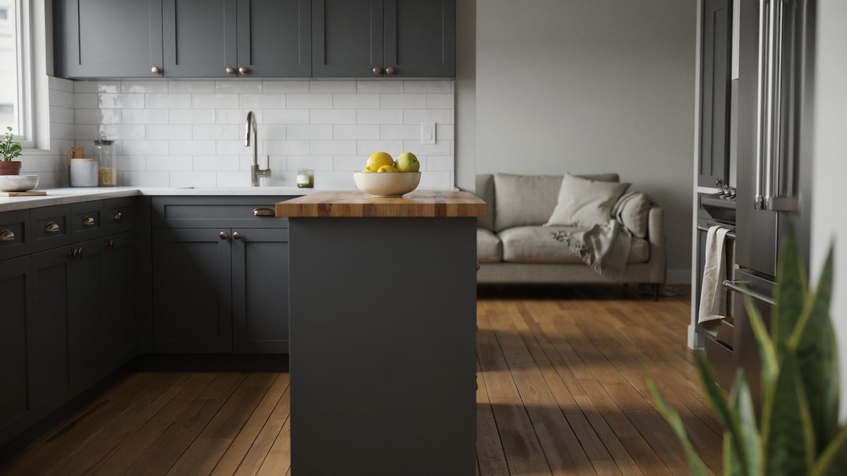 Charcoal cabinets and a butcher block island sit beside a linen sofa