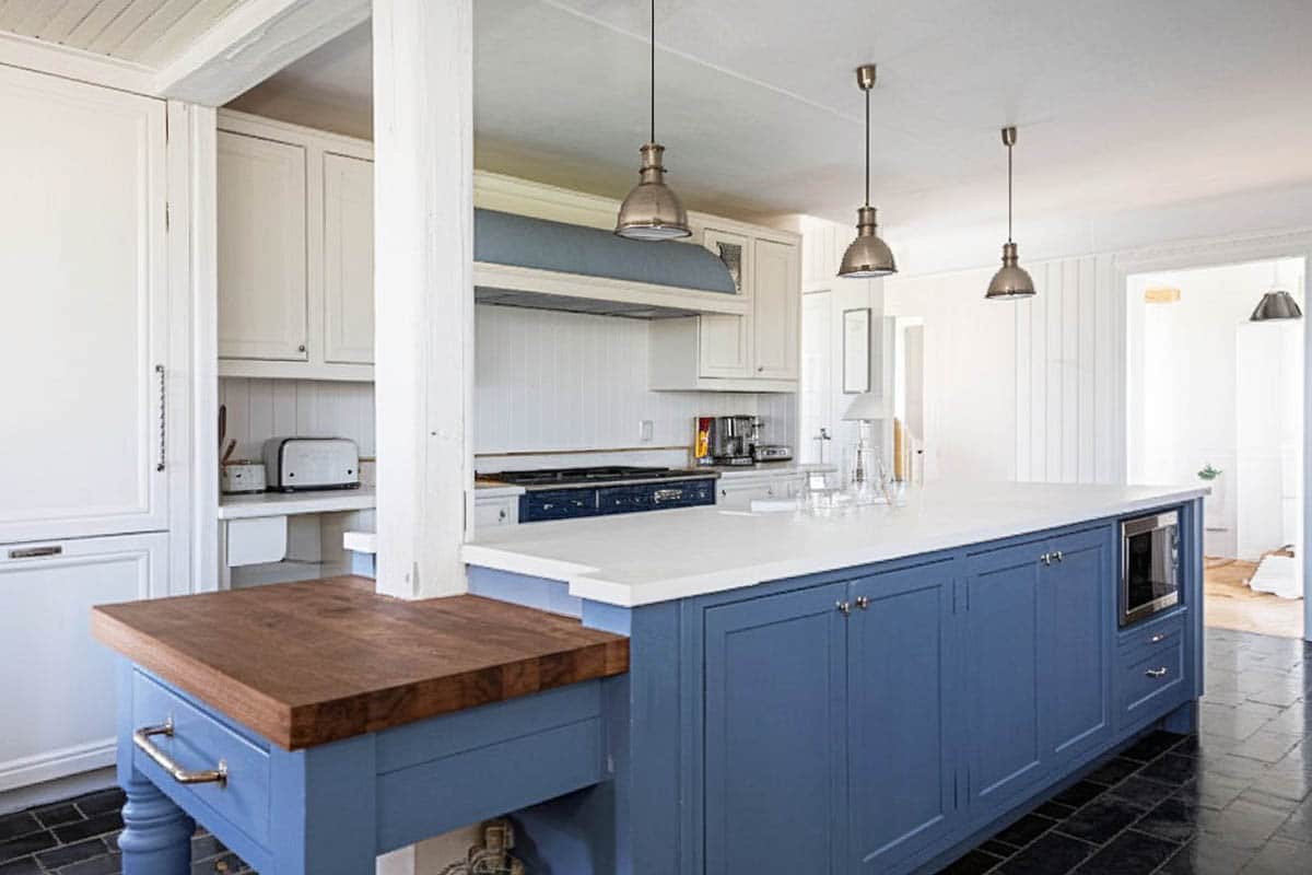 Traditional kitchen with white cabinets, blue island with support beam