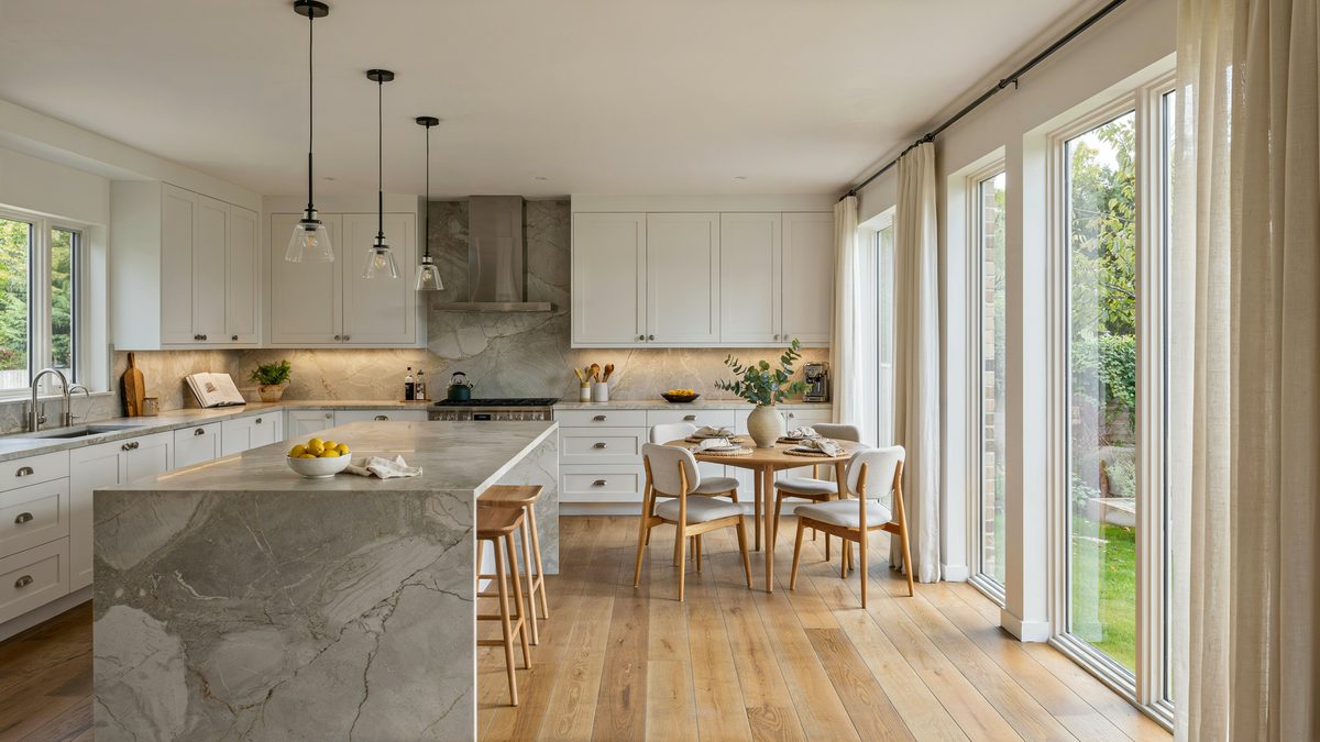 Open plan kitchen with marble island flowing into a sunlit oak dining area