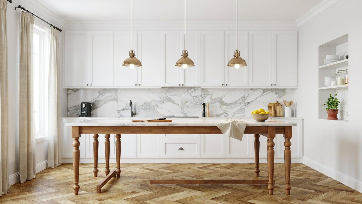 Turned leg wood table island beside white cabinets and marble slab backsplash