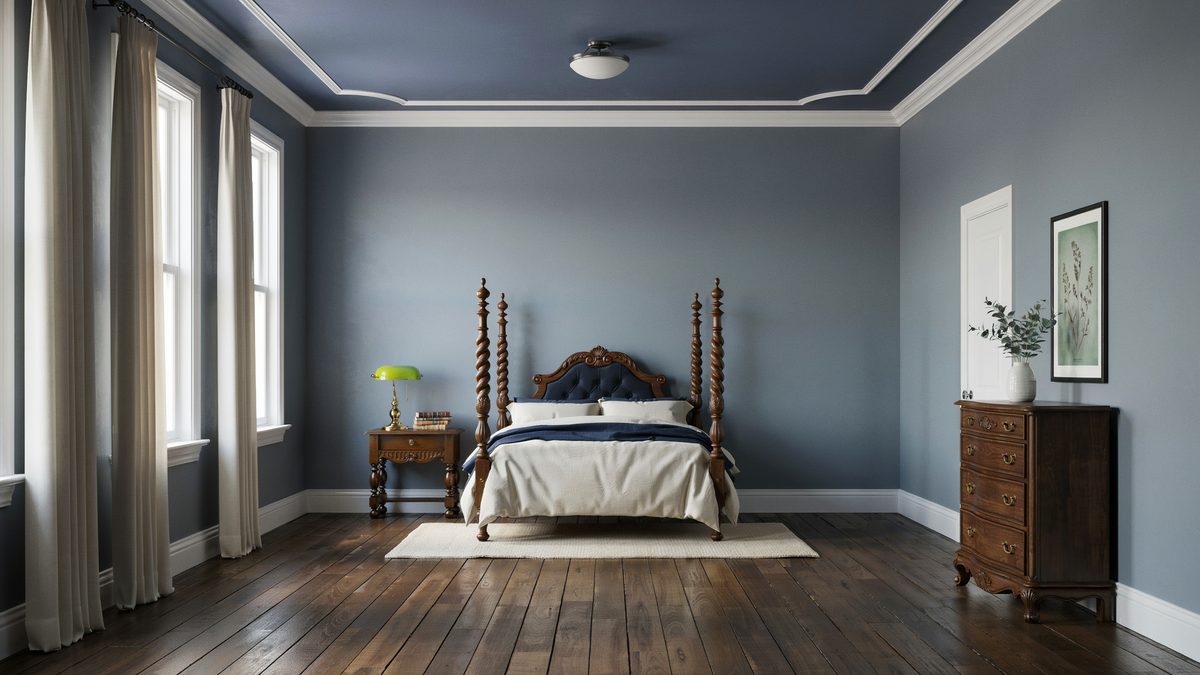 Blue walls and a painted tray ceiling with a carved wood bed and dresser