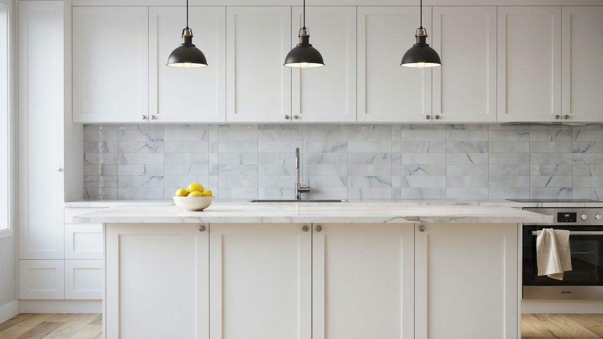 Marble tile backsplash behind white cabinets with three black dome pendant lights