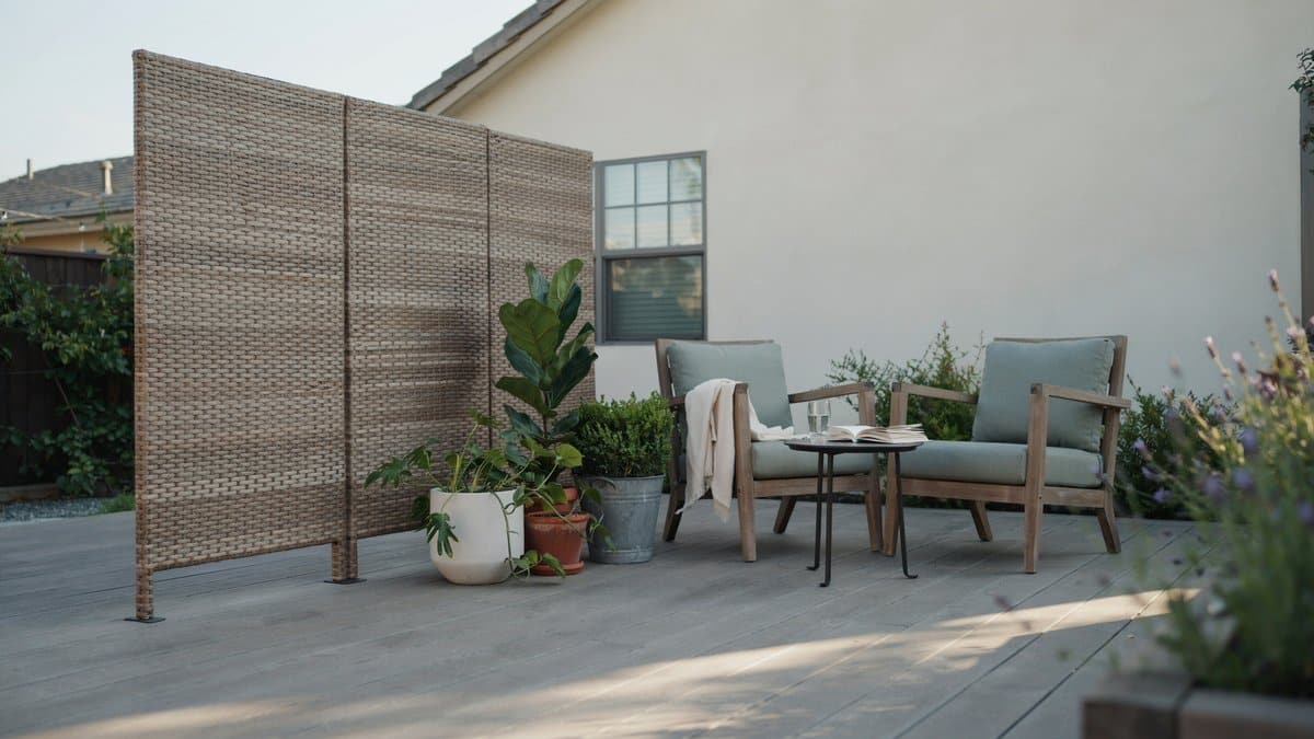 Woven resin screen panel standing beside two patio lounge chairs