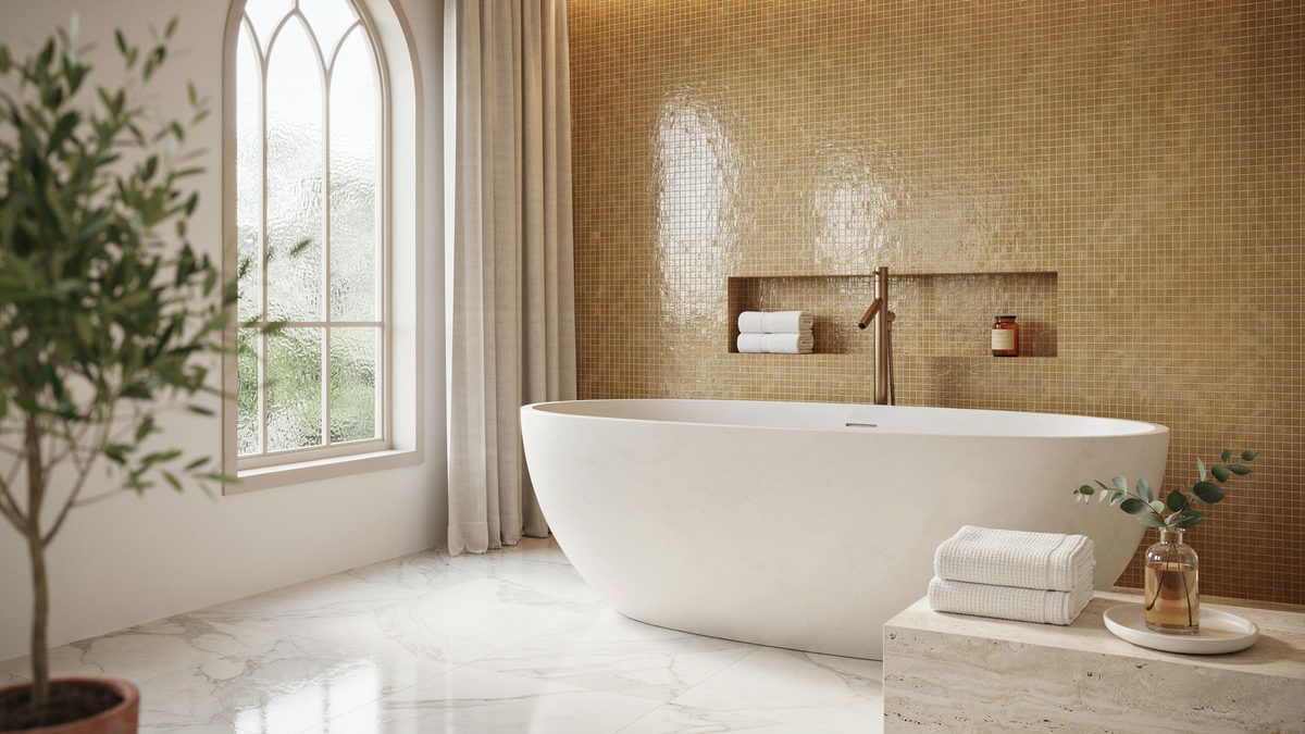 Freestanding oval tub set against a gold mosaic tile wall and marble floor