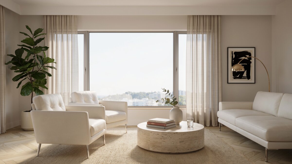 White leather armchairs and a chaise around a round stone table by a window
