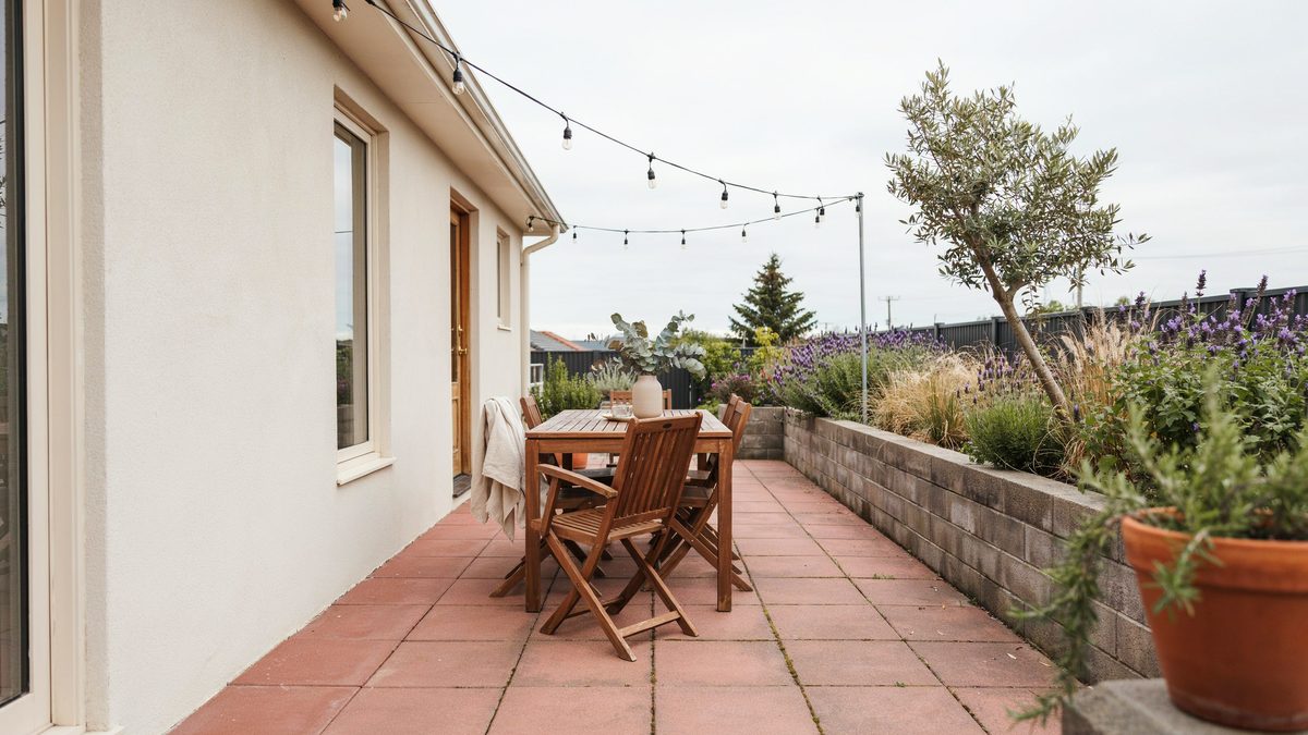 Terracotta patio stones on a raised terrace with a wood dining set