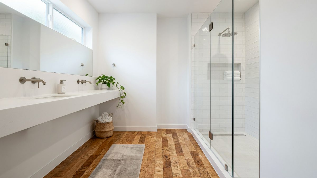 Warm cork plank floor running past a long trough sink to a glass shower