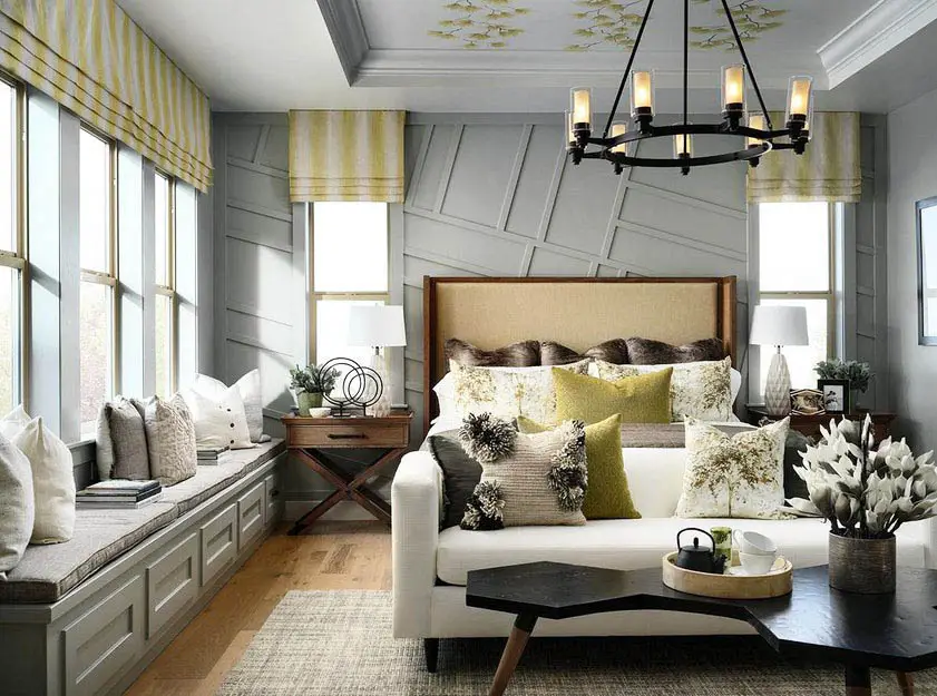 Bedroom with gray seat benches, yellow Roman shades and colorful cushions