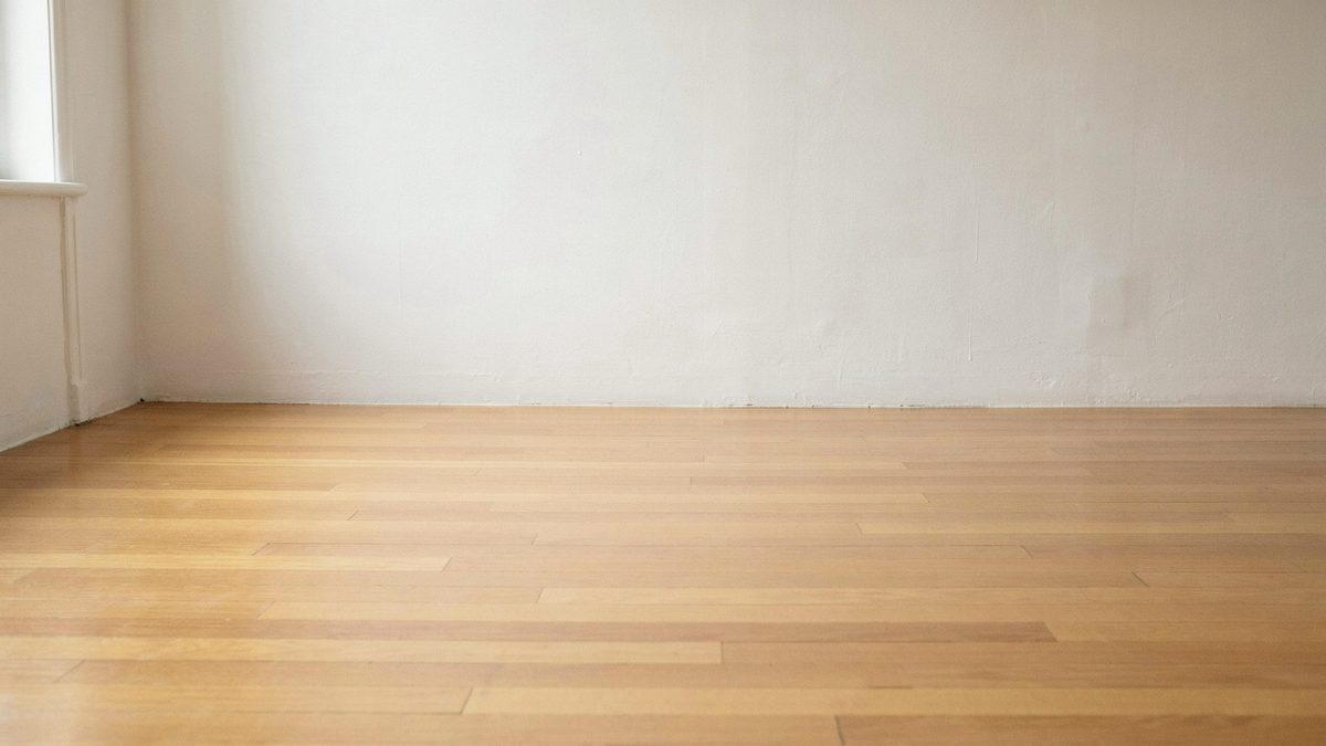Close view of pale beech floorboards meeting a plain white wall