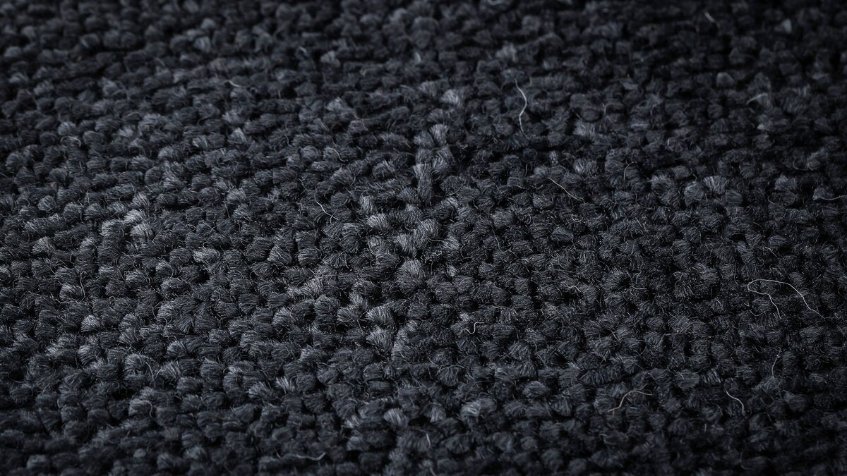 Close up of dense black polyester carpet fibers with a soft sheen