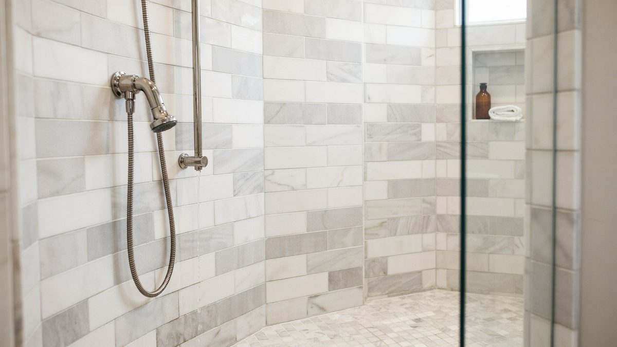 Marble subway tile shower in white and gray with handheld sprayer on a slide bar