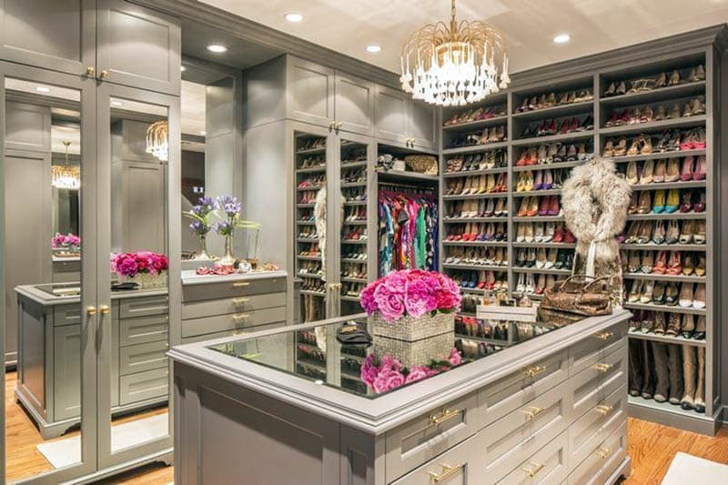 Contemporary closet with shoe racks, island, chandelier and gray cabinets