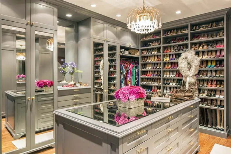 Contemporary closet with shoe racks, island, chandelier and gray cabinets