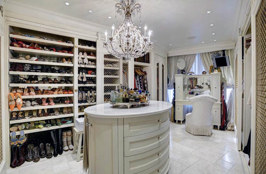 Luxury walk in closet with shoe racks, oval island, chandelier and vanity makeup station