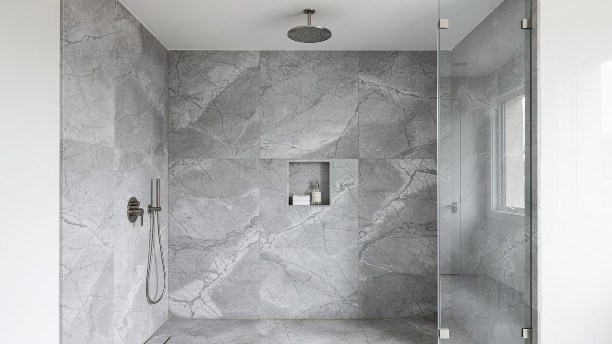 Gray marble shower wall panels with rainfall head, recessed niche and frameless glass