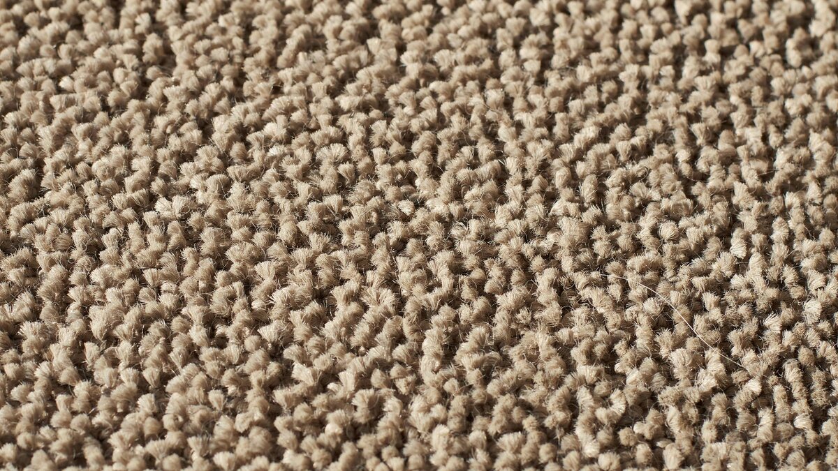 Cut pile carpet close up with evenly trimmed fibers in warm taupe