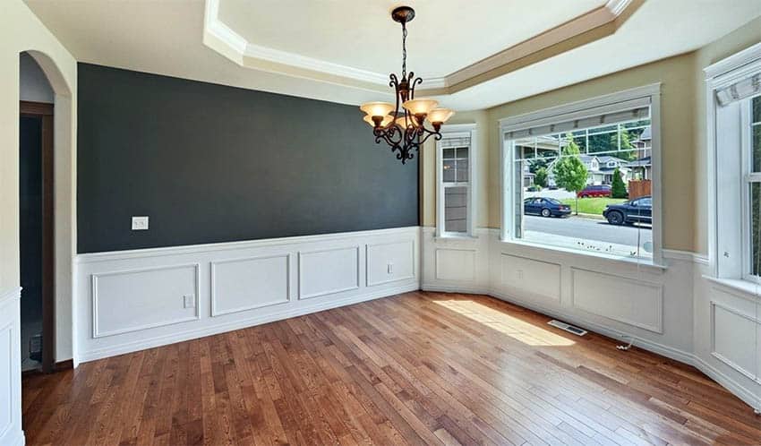Dining room with black accent wall beige paint and white wainscoting