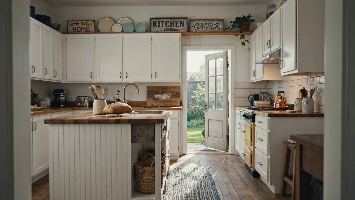 Wooden signs sit above white cabinets facing a wood topped beadboard island