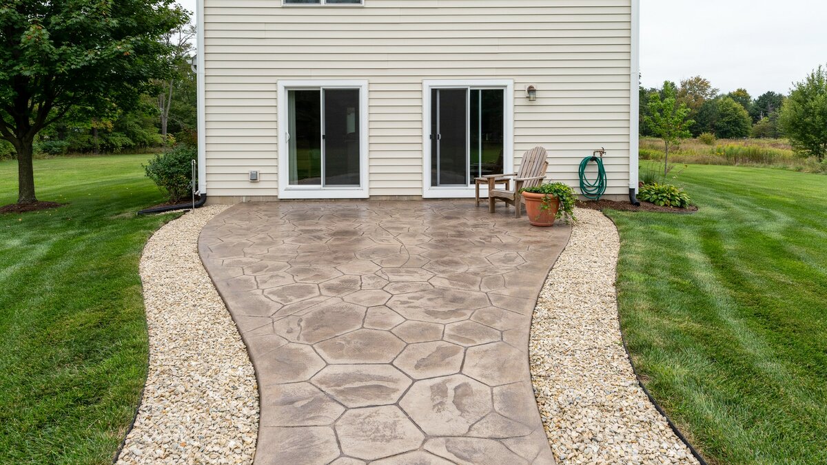 Stamped concrete paving shaped like stone and edged with a pea gravel band