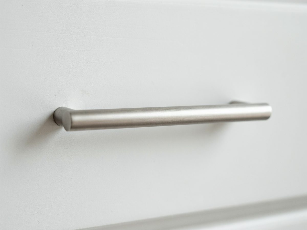 Rounded nickel finish bar pull on a plain white cabinet face