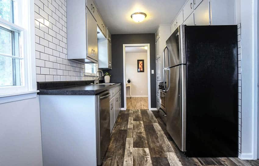 Galley kitchen and white brick backsplash and black countertop