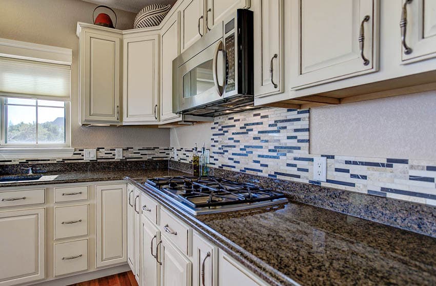 kök med antika vita nödställda dörrskåp mörkbrun granit