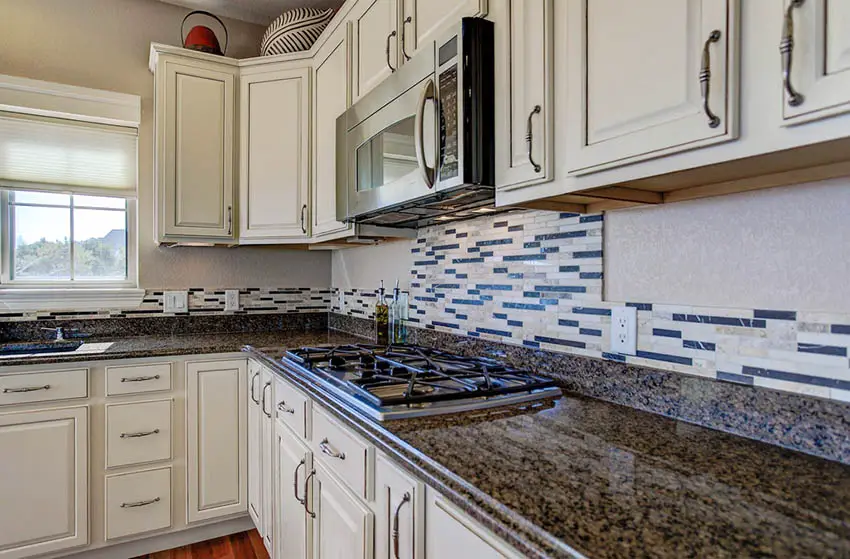 Kitchen with antique white distressed door cabinets and dark brown speckled granite
