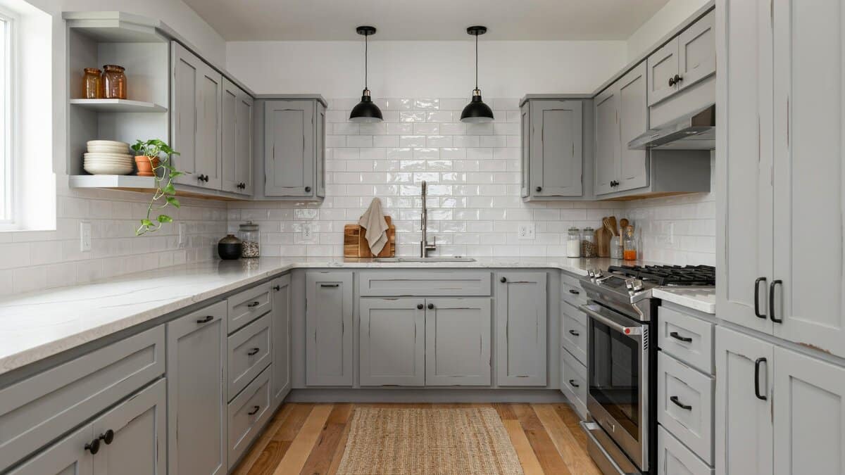 U shaped kitchen lined with distressed gray cabinets and white subway tile