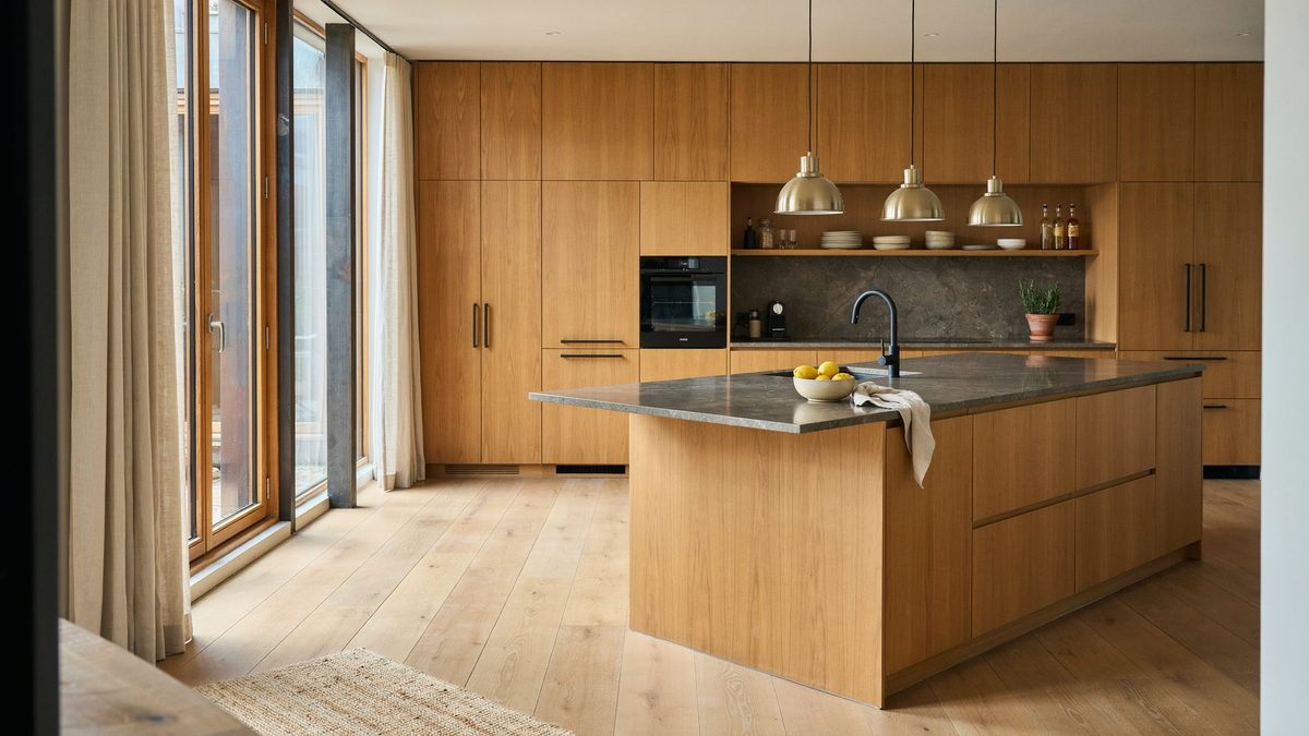 Walnut wall cabinets and an angled island topped with dark granite