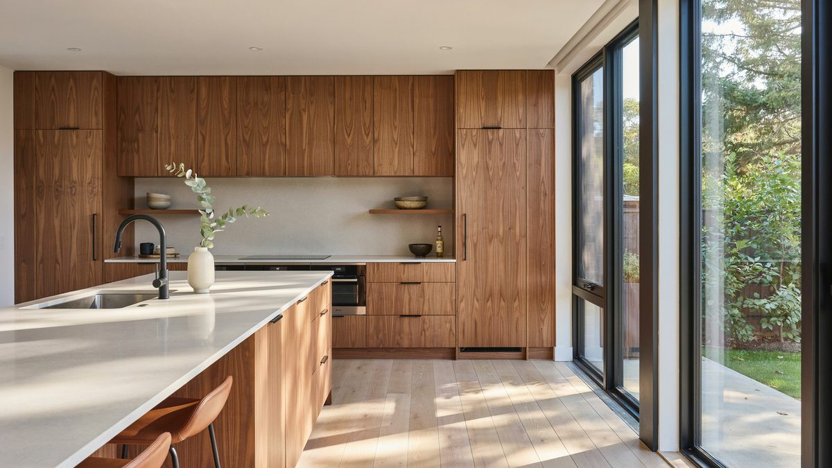 Wood veneer cabinets with push to open doors beside floor to ceiling glass