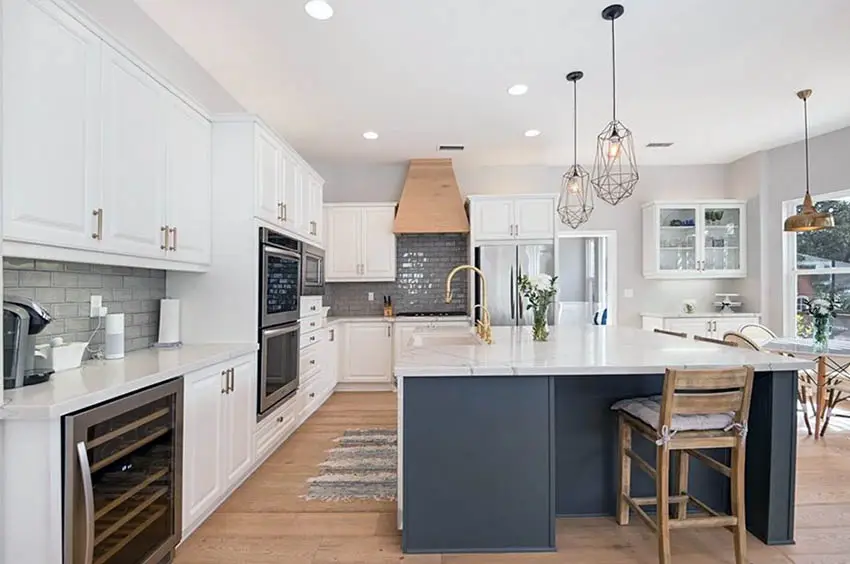 Kitchen with white cabinets, dark gray island marble countertops and glass subway tile
