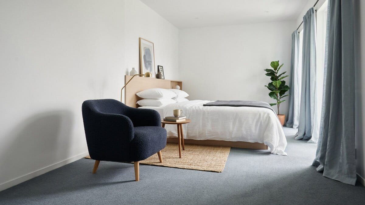 Blue wall to wall carpet in a contemporary bedroom with a sitting area