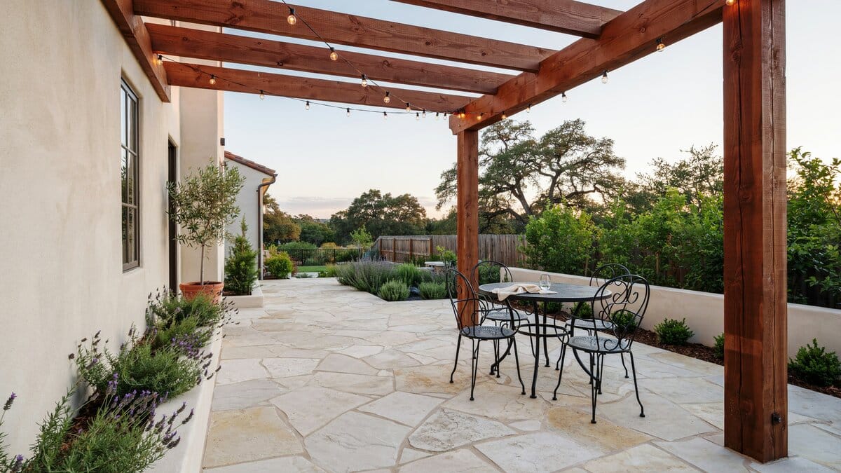 Limestone paved terrace under a redwood pergola hung with warm string lights