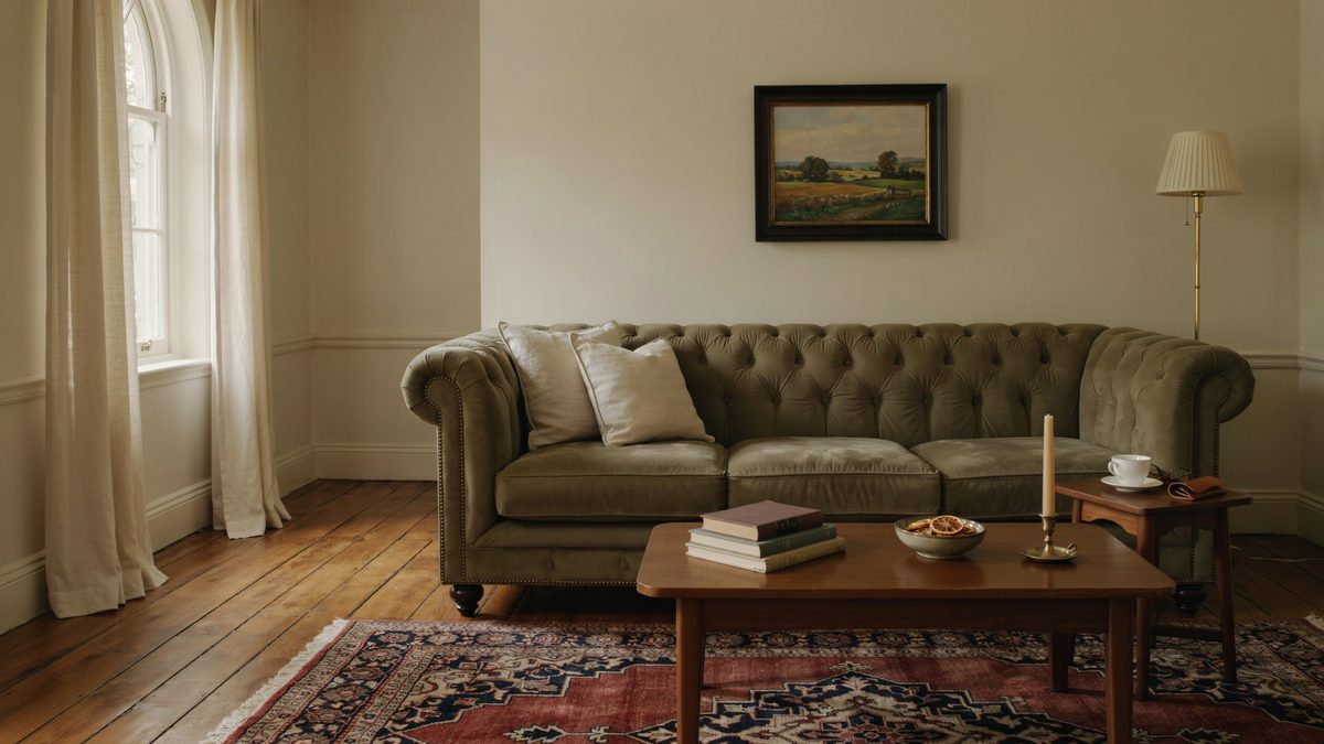 Chesterfield sofa and a patterned rug resting on golden teak boards