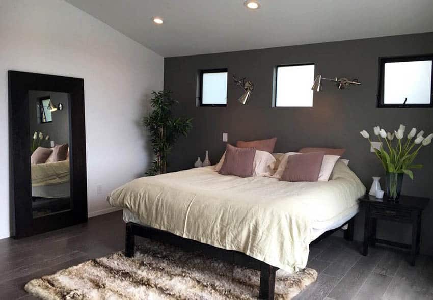 Loft bedroom with dark gray wall, and mirror with black frame 