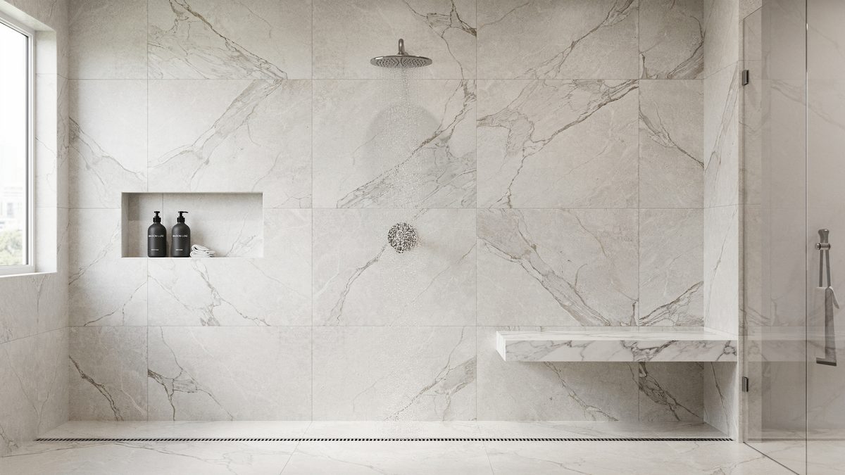 Large marble field tile shower with floating bench, lit niche and linear floor drain