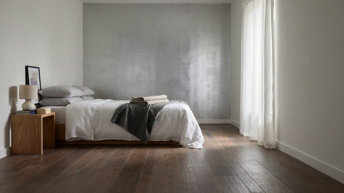Bedroom with a silver plaster wall above dark walnut floorboards