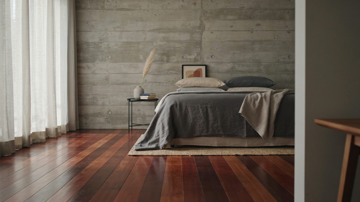 Concrete walled bedroom with glossy Brazilian cherry floors and gray bedding