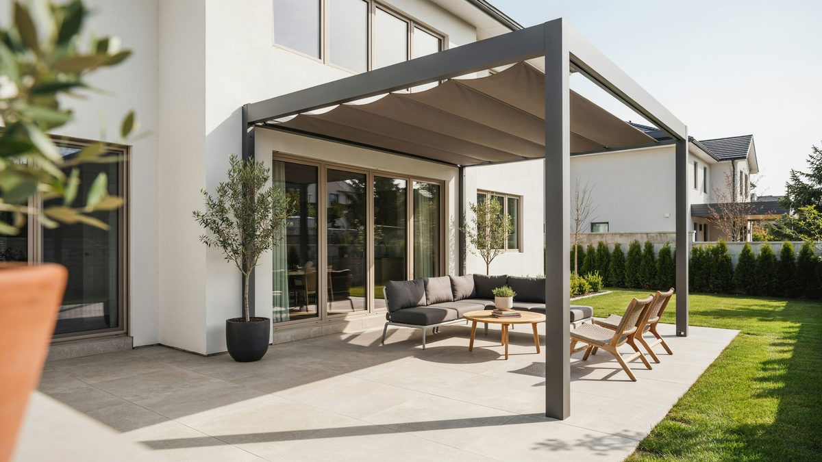 Gray retractable canopy pergola against a white modern home and lawn