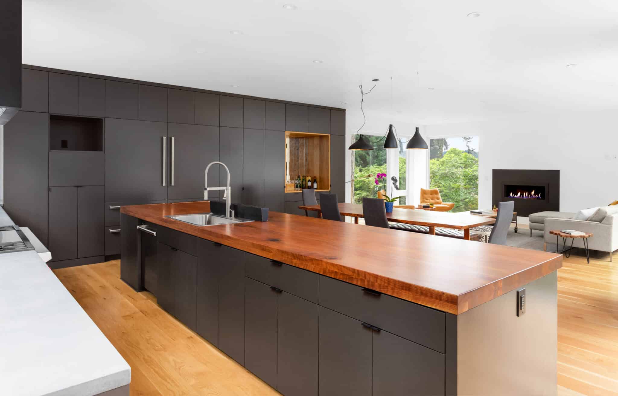 Modern kitchen with black cabinets and wood countertops and white quartz counters