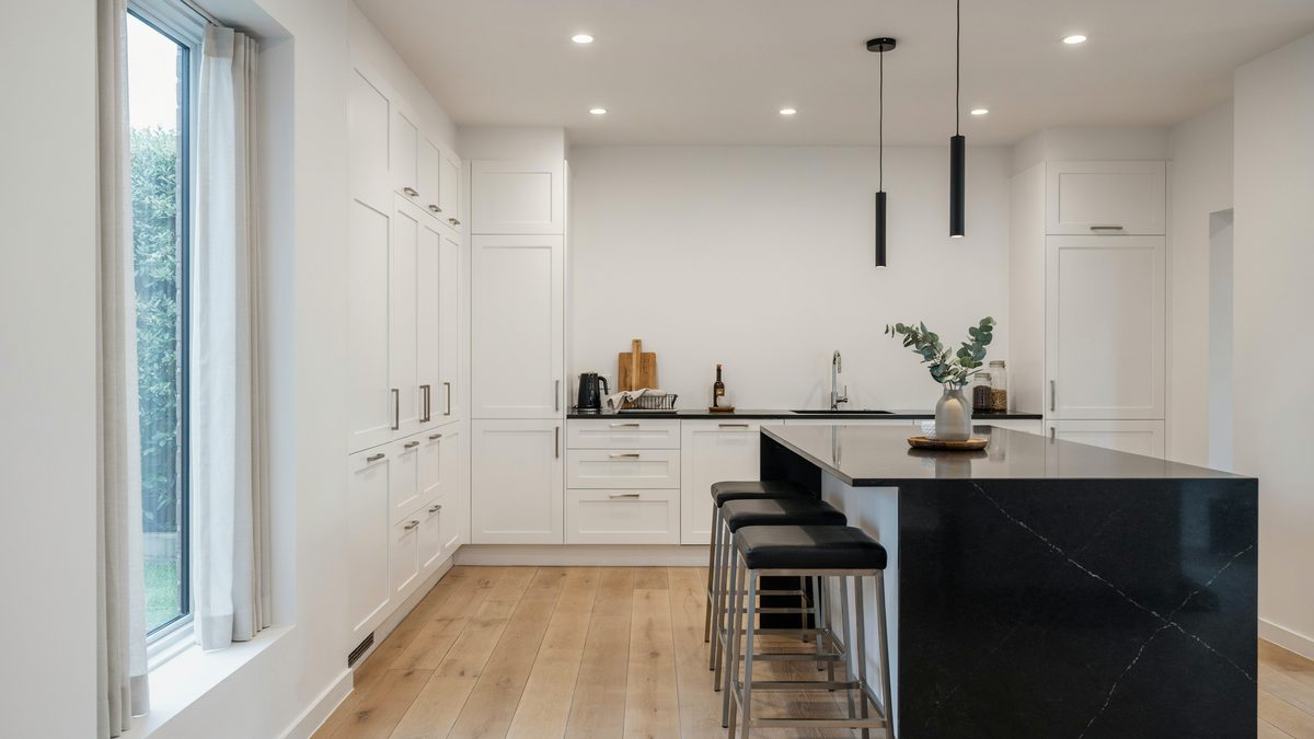 White cabinets with polished metal pulls and a black stone peninsula